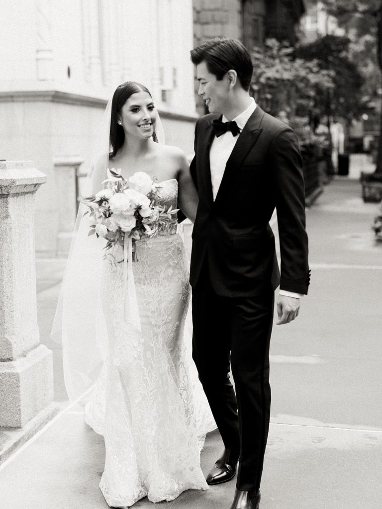 Black and white image of a bride and groom walking down the streets of New York.