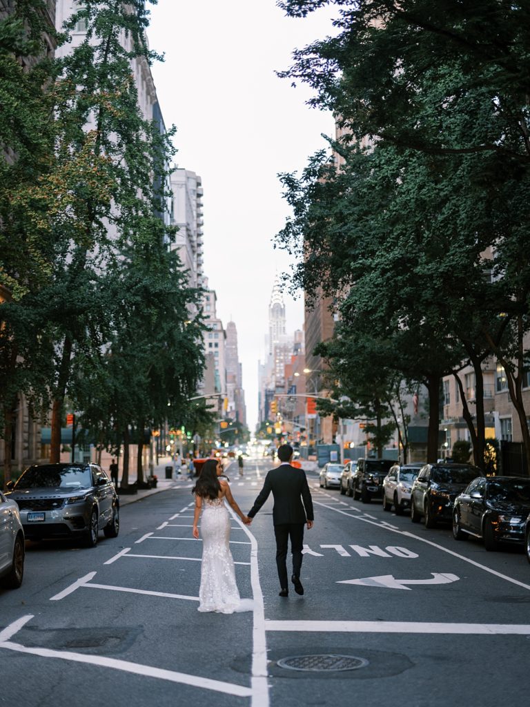 Bride and groom standing in street holding hands in New York City.