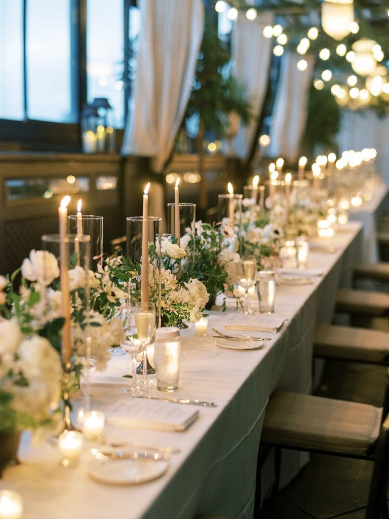 Detail shot of a dinner table at a wedding with candles and white & green florals.