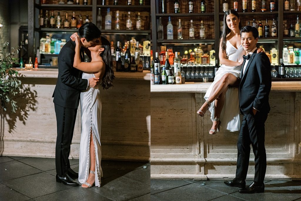 Bride in silk dress and groom in tux pose on bar.