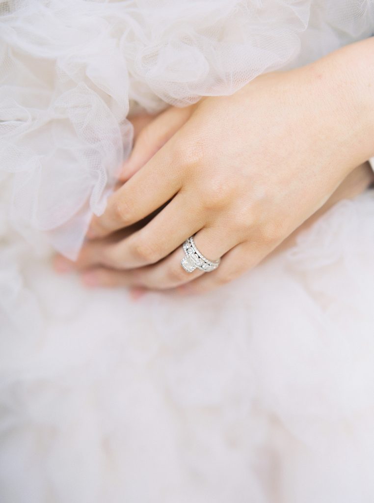 Woman's hand with beautiful engagement ring against a tulle dress.