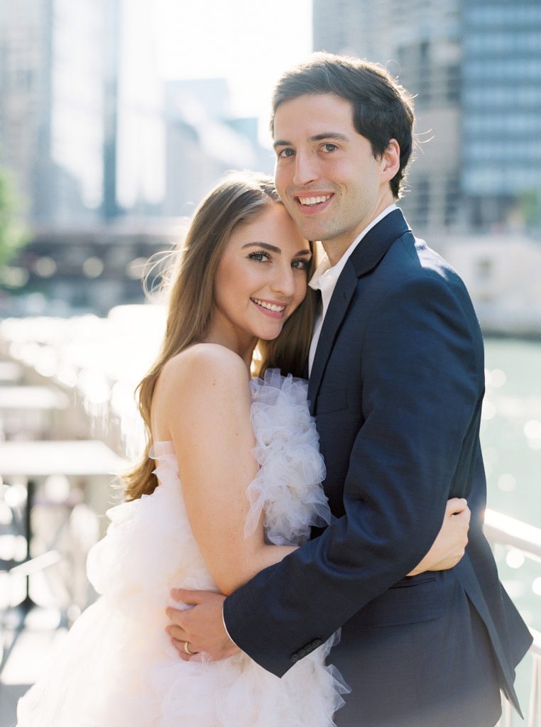 Woman and man hugging in formal clothes with downtown Chicago out of focus behind them.