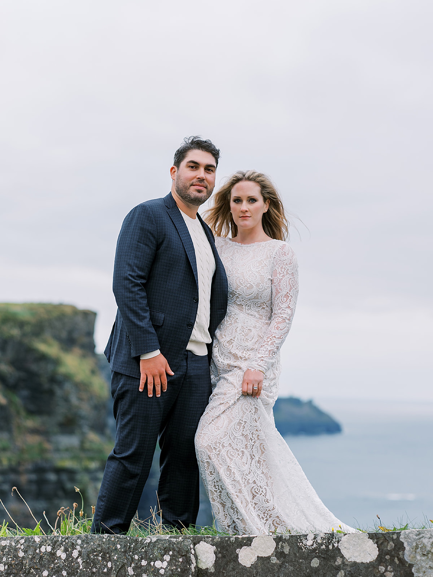 Engaged couple standing on the cliffs of Moher for their Irish engagement session.