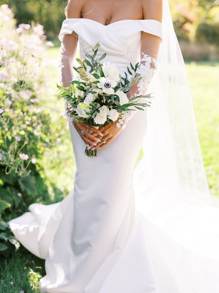 Bridal bouquet of flowers held by a bride in front of her modern wedding dress.