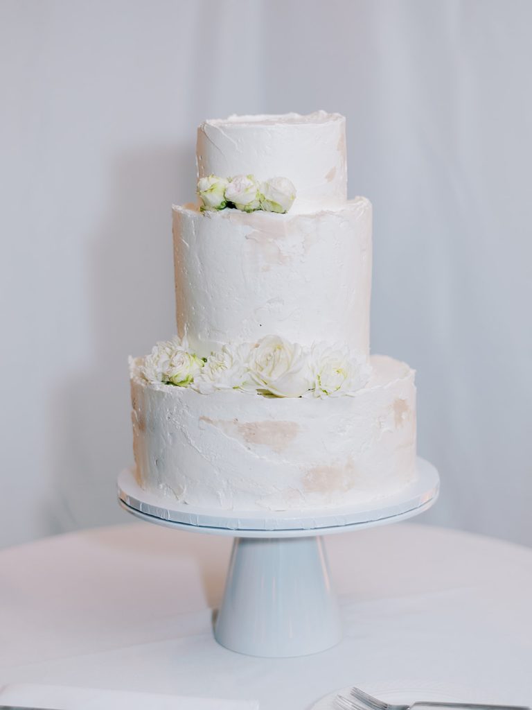 Simple, modern three tier white cake at a wedding reception. Shot by NYC Wedding Photographer, Sophie Kaye.