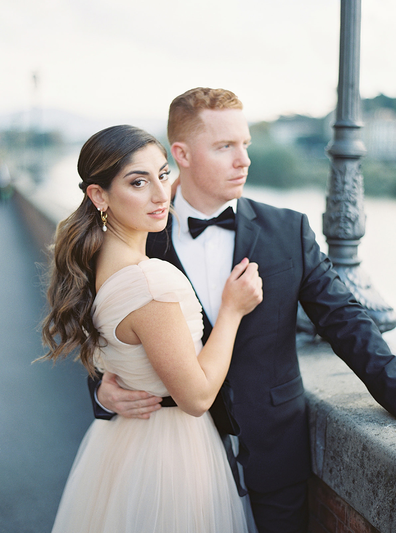 woman wears luxury wedding dress on Italian bridge with new husband wearing suit and tie