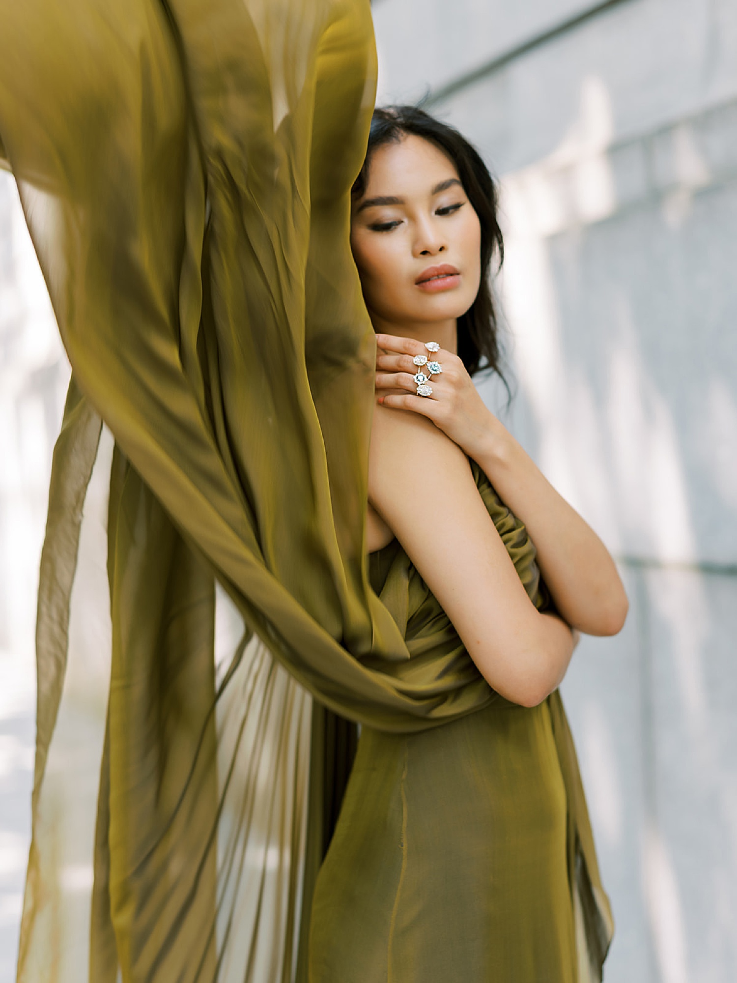 model wearing olive green dress showing off diamond rings for editorial campaign 