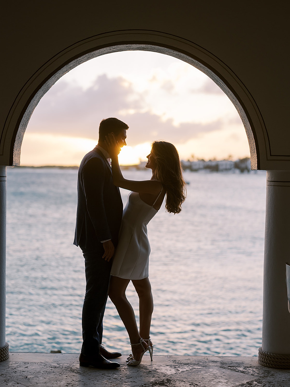 newlywed bride and groom pose at sunset in resort hotel balcony over ocean shot by destination luxury photographer