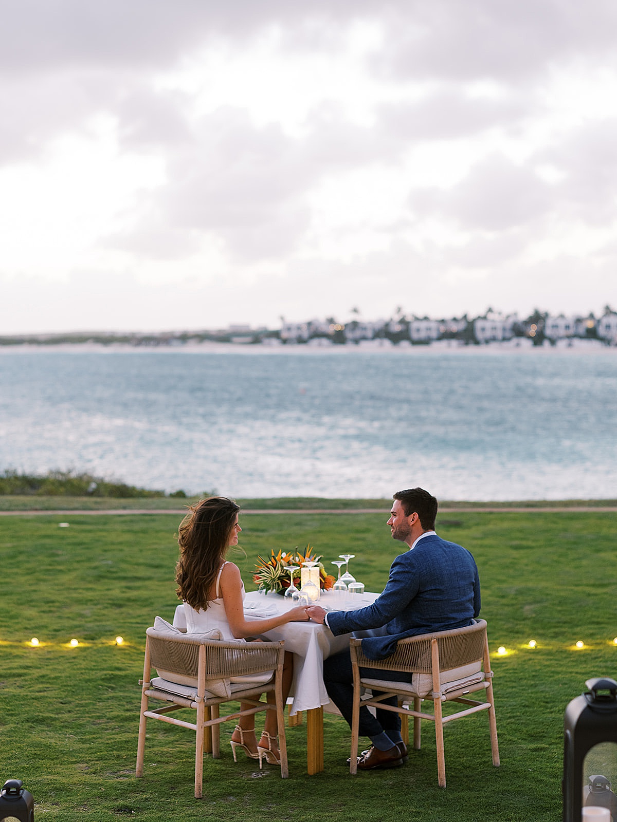 bride and groom share dinner for two on romantic lawn overlooking ocean at elopement shot by destination luxury photographer