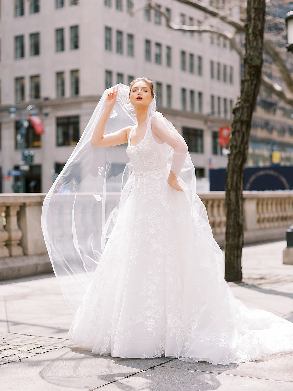 bride in long veil and lace embellished wedding gown poses for NYC Fashion Photographer