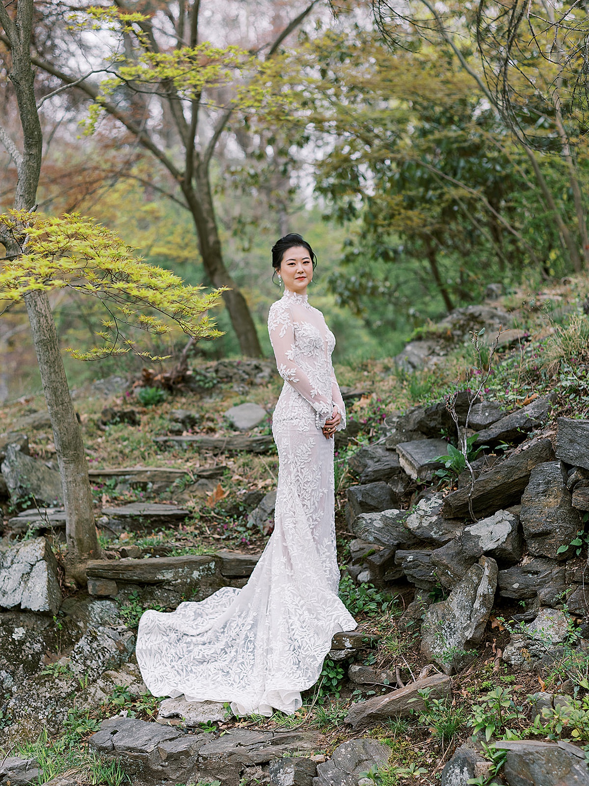 Bride with couture gown and long train poses outside in lush garden during Westchester Blue Hill Wedding
