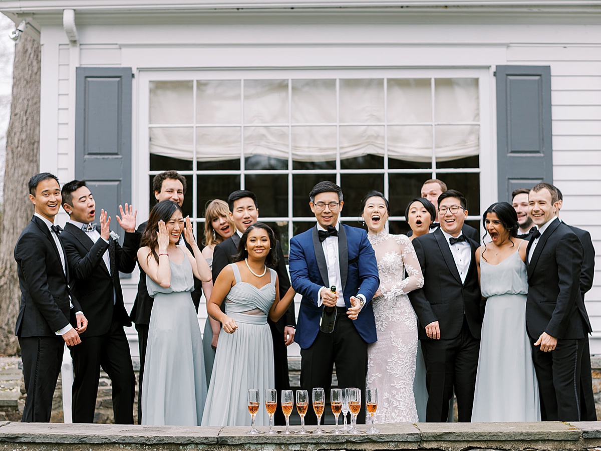 Wedding party celebrates with champagne before outdoor black tie wedding shot by Destination Luxury Photographer