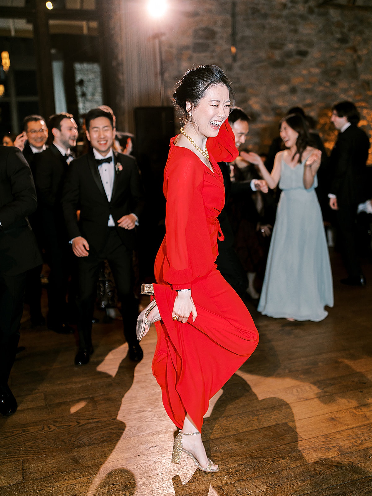 Bride in elegant red evening gown celebrates with a dance at black tie wedding reception shot by Sophie Kaye Photography